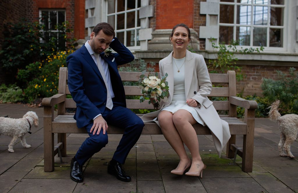 Man and woman sitting on a bench with dogs