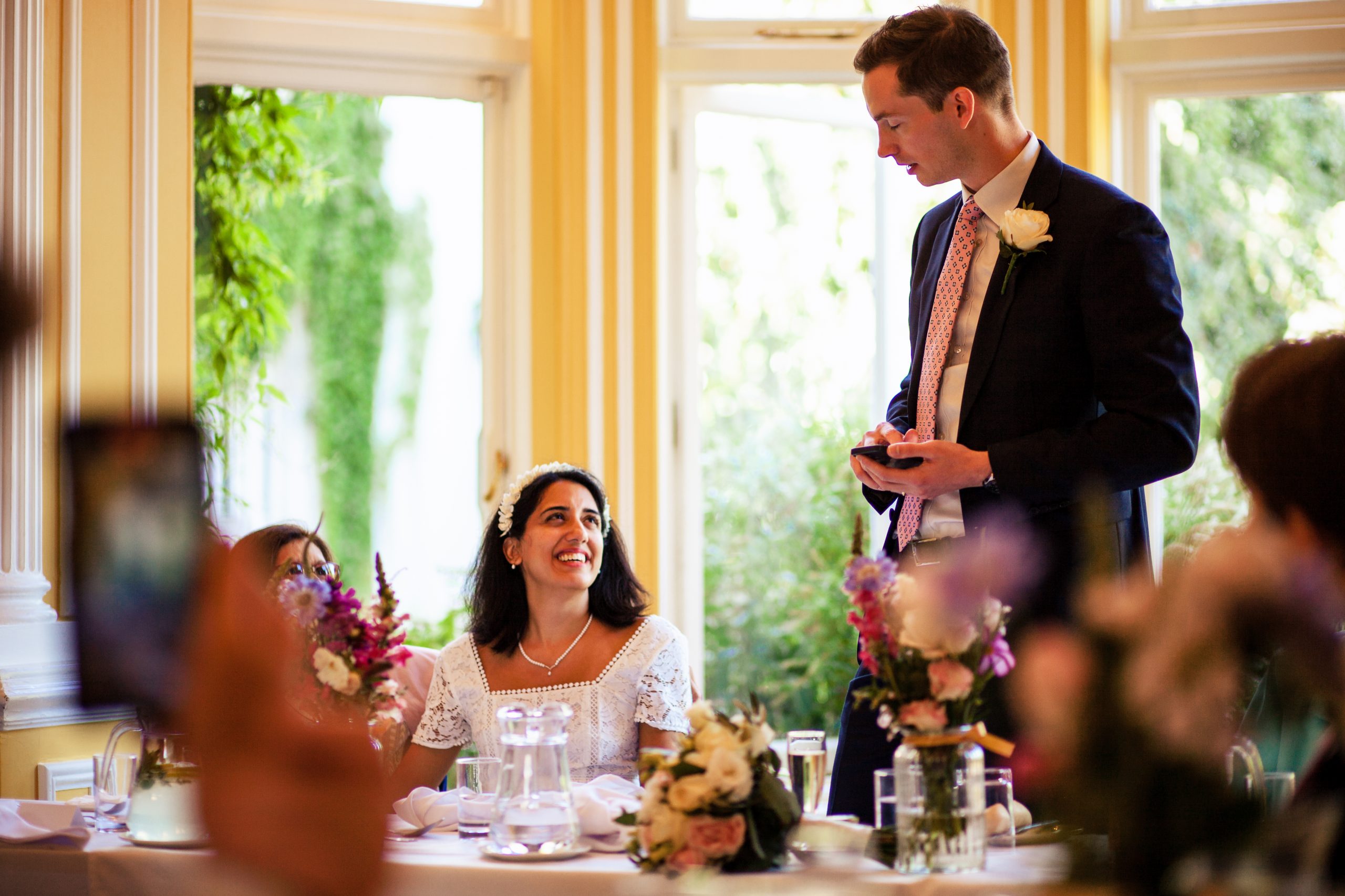 Groom delivering a speech with bride smiling at him